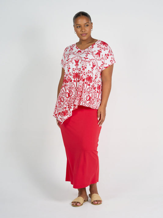 Woman wearing a red and white patterned top with a red skirt on a white background