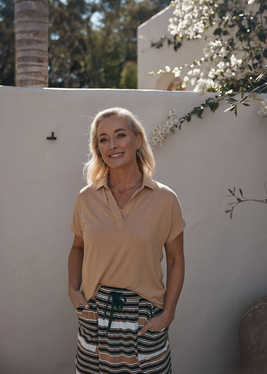Lou Lou Australia Rush Bamboo Short Sleeve Collared Polo Top in Tan, paired with striped drawstring pants.