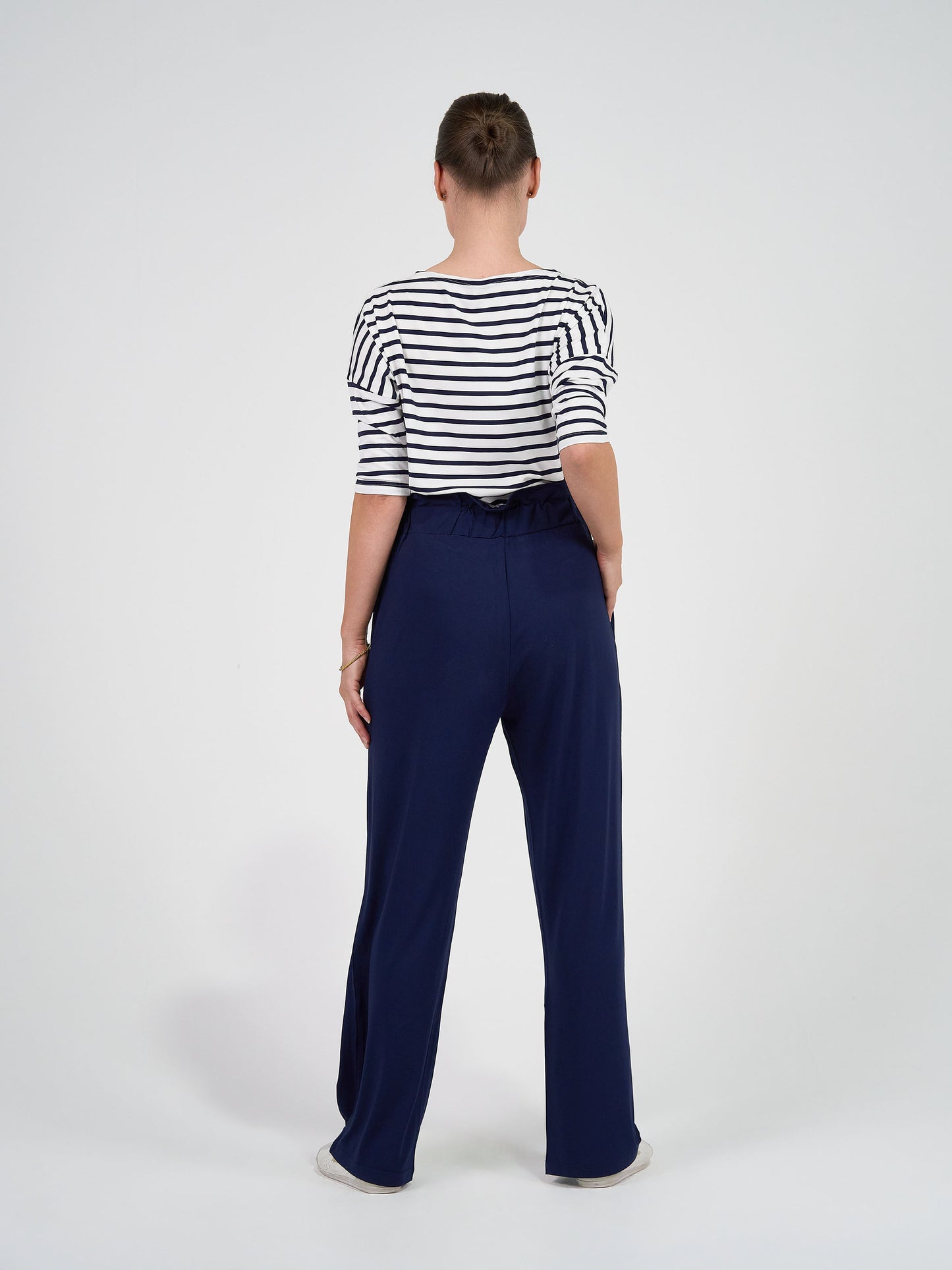 A person faces away from the camera, wearing the Camila 3/4 Sleeve Bamboo Top in navy and white stripes with loose navy blue pants, against a plain white background.