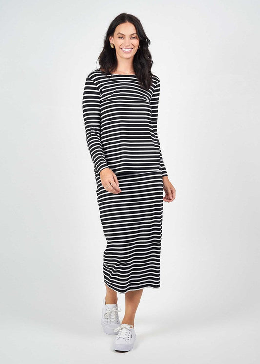 A woman smiles in the Adele Long Sleeve Bamboo Top - Black & White Stripe, paired with white sneakers, standing against a plain light background.