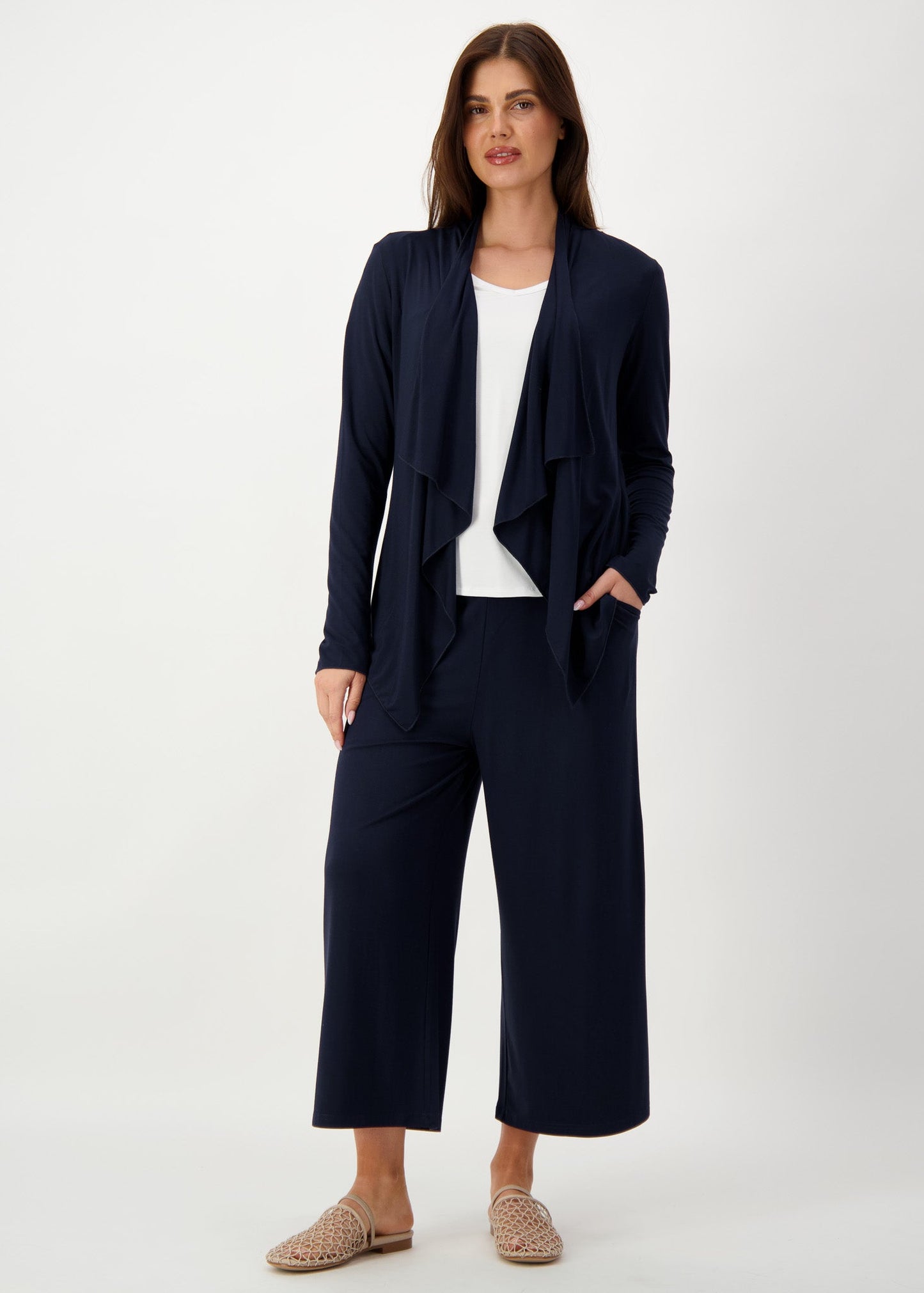 A woman wearing a navy bamboo waterfall jacket over a white top & a black relaxed pants with a brown sandals (Product image)