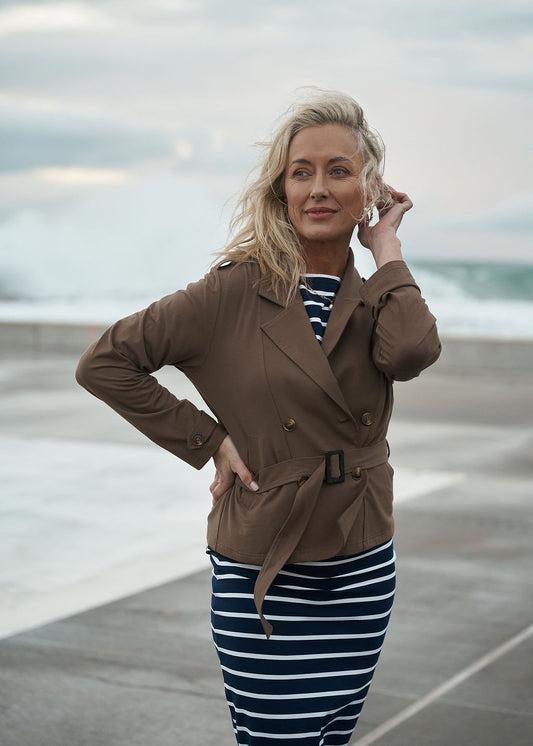 Lou Lou Australia Sofie Cropped Bamboo Trench Coat in Chocolate, belted over a navy and white striped dress.
