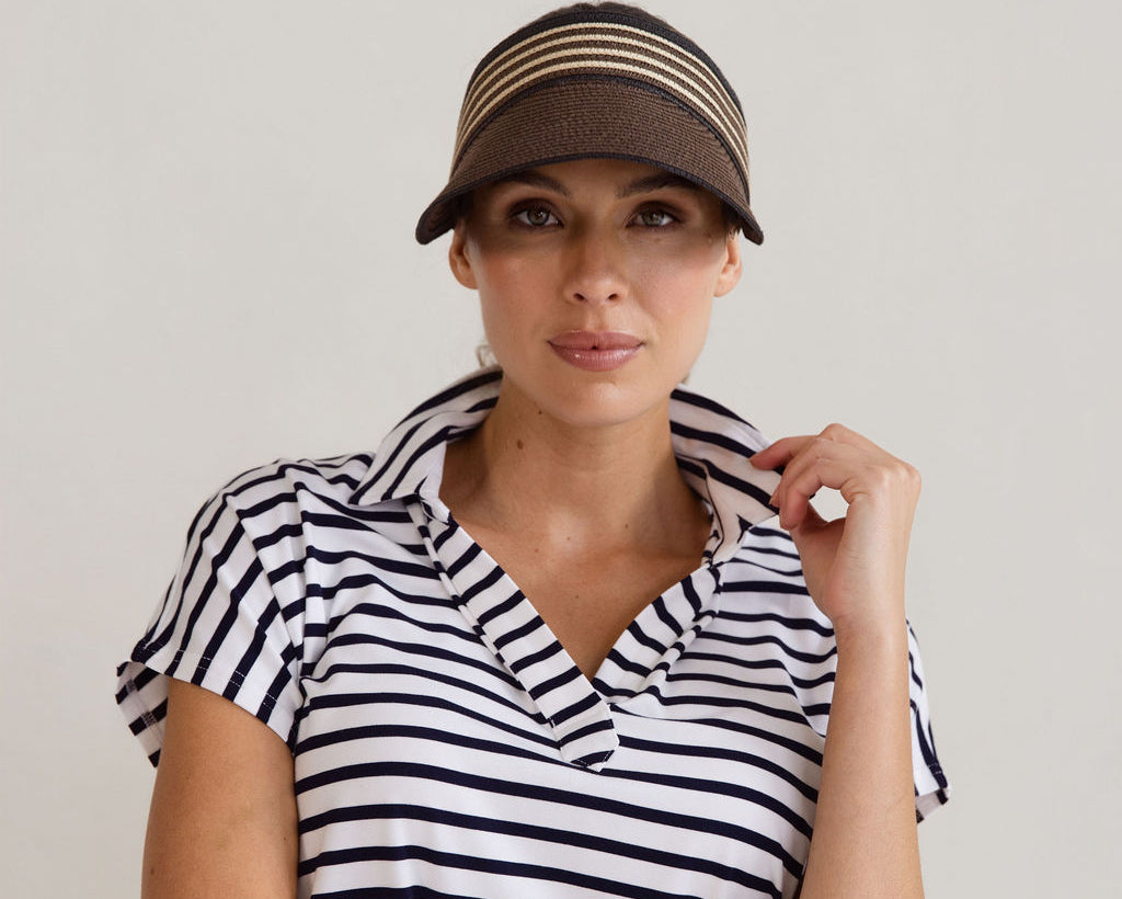 Woman wearing a brown striped cap and the Rush Bamboo Short Sleeve Collared Polo Top in navy and white stripe, looking directly at the camera with a neutral expression.